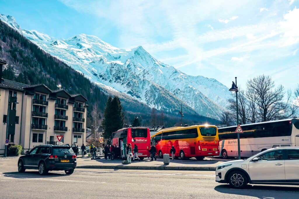 3 bus garés sur fond de montagne ensoleillée.