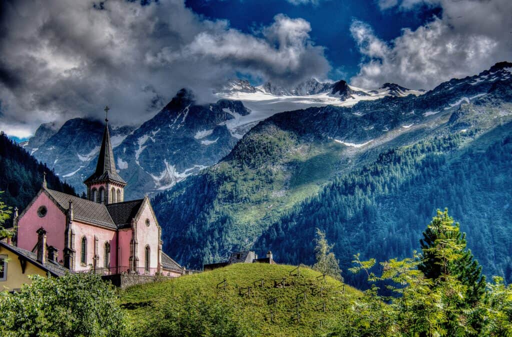 A pink church stands out in front of a moody mountain backdrop