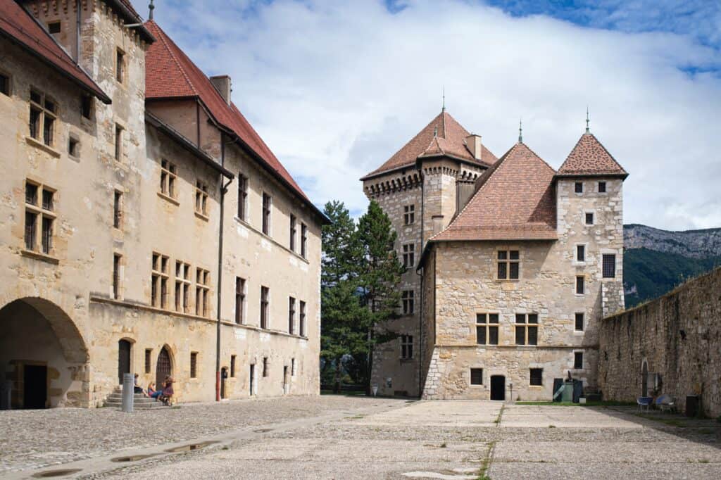 Musée-Chateau D'Annecy, un ancien château construit de pierres et de briques beiges dans un paysage montagneux. 