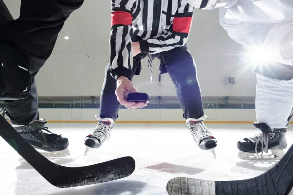 Un arbitre de hockey sur glace place un palet sur la glace.