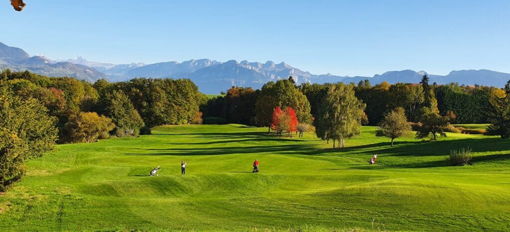 Parcours de golf vallonné, vue sur les montagnes.