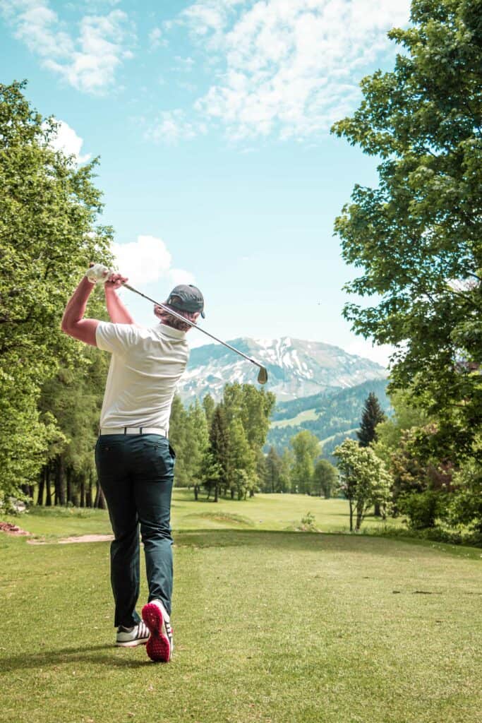 A golfer seen from behind, playing with view on the mountains.
