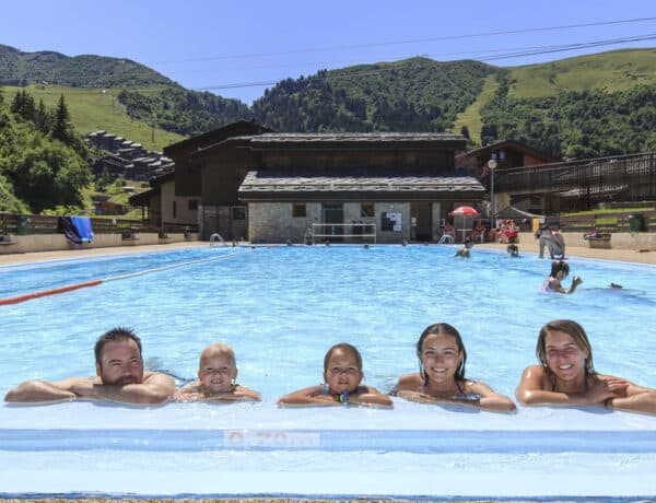 Une famille dans une piscine, avec les montagnes derrière.