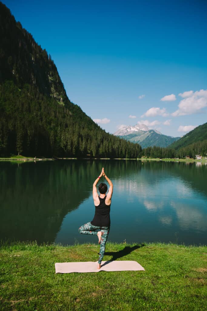 Une femme en position de yoga face au Lac Montriond.