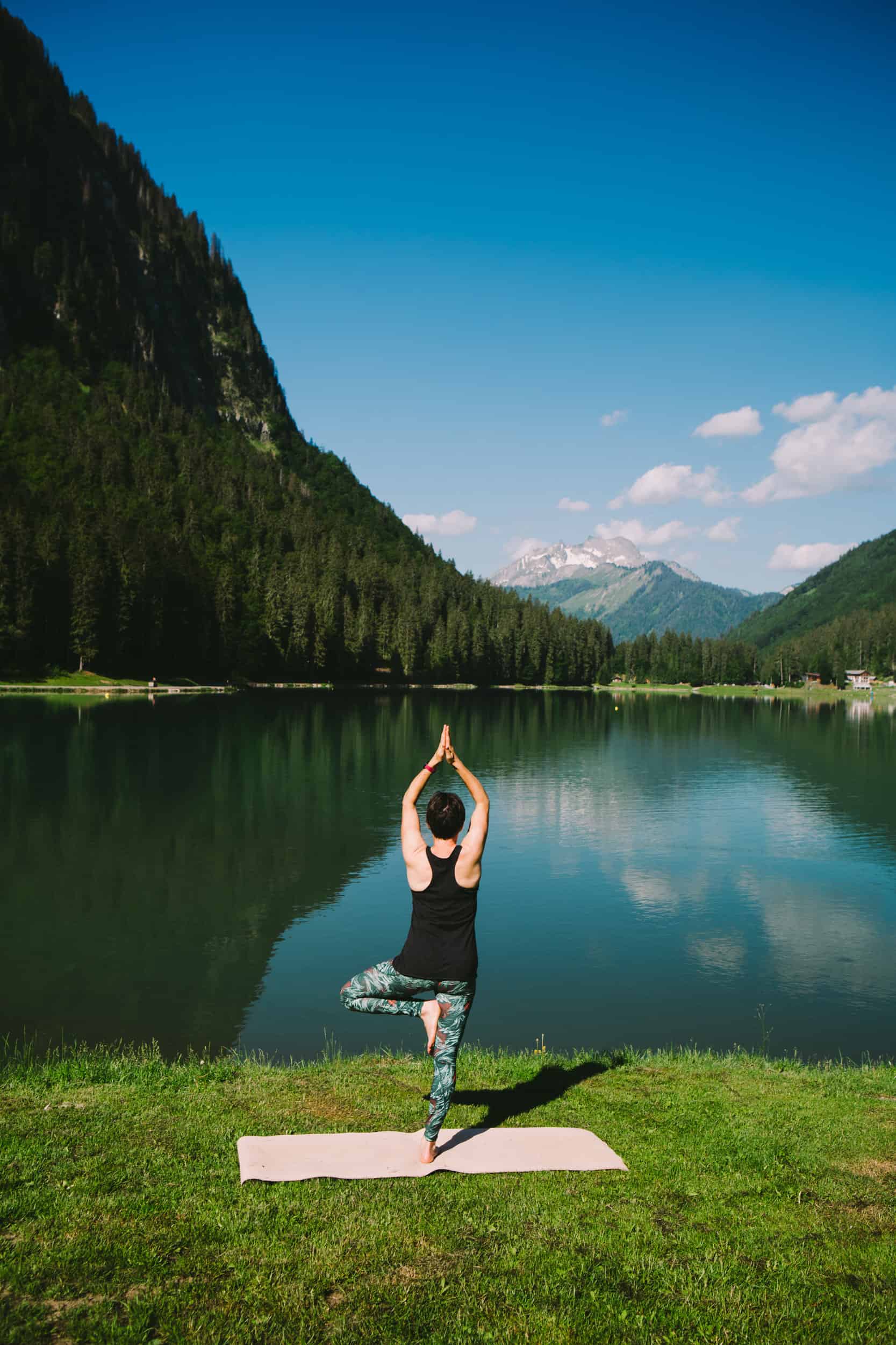 Une femme en position de yoga face au Lac Montriond. 