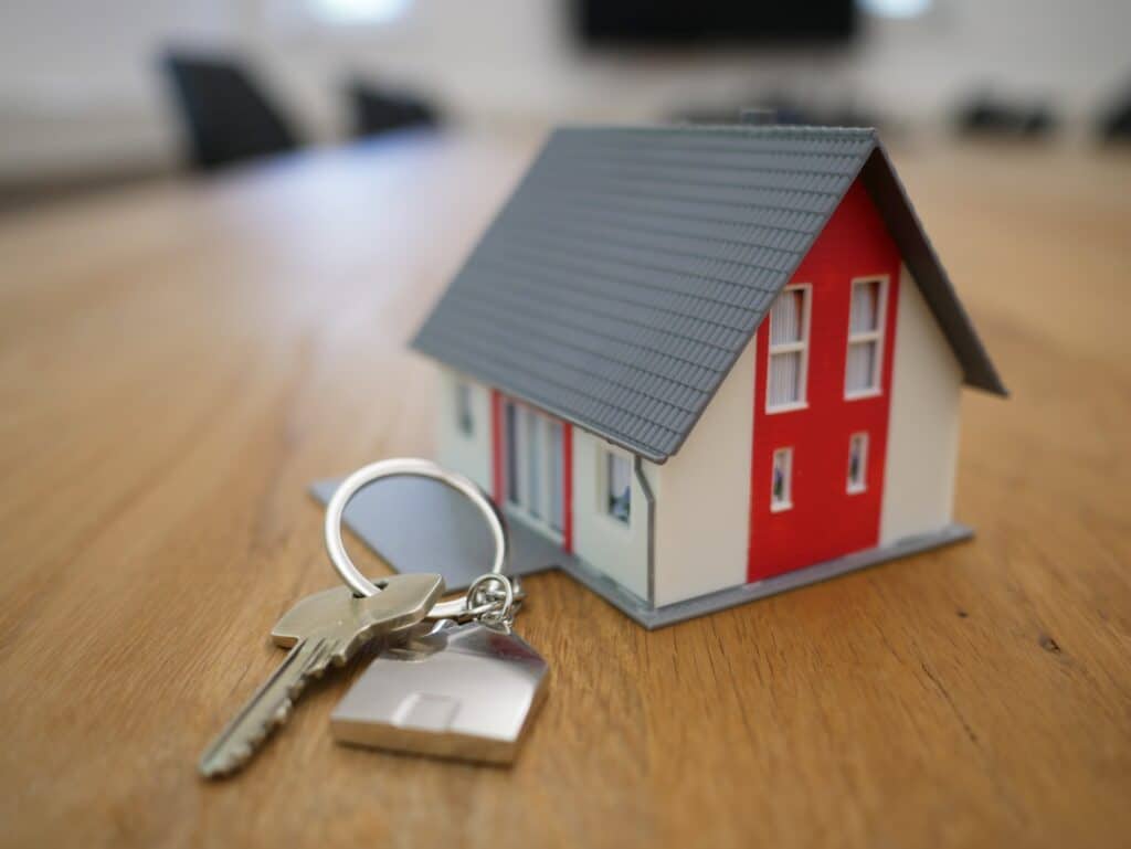Image representing property investment, with a model house and keys.