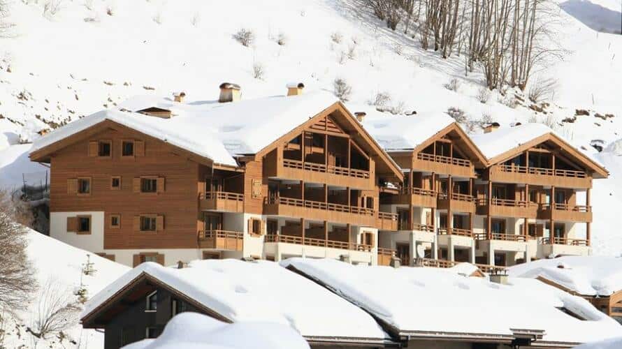 Extérieur de la Résidence de location Les Grandes Alpes à La Clusaz au milieu de la station enneigée.