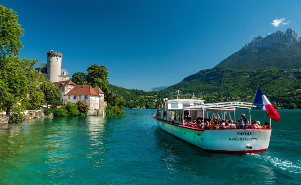 Un bateau sur le lac d'Annecy en été, s'approchant d'un château.