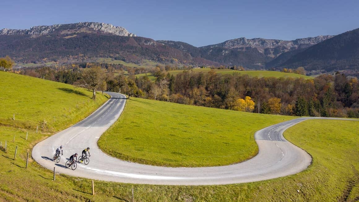 Trois cyclistes dans une route à lacets, en moyenne montgane, près d'Annecy.