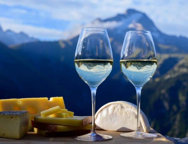 Verres et vin blanc et fromages sur fond de montagne.
