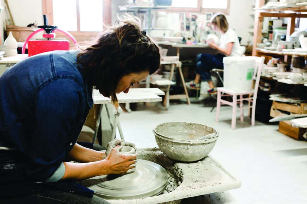 A woman makes pottery on a wheel