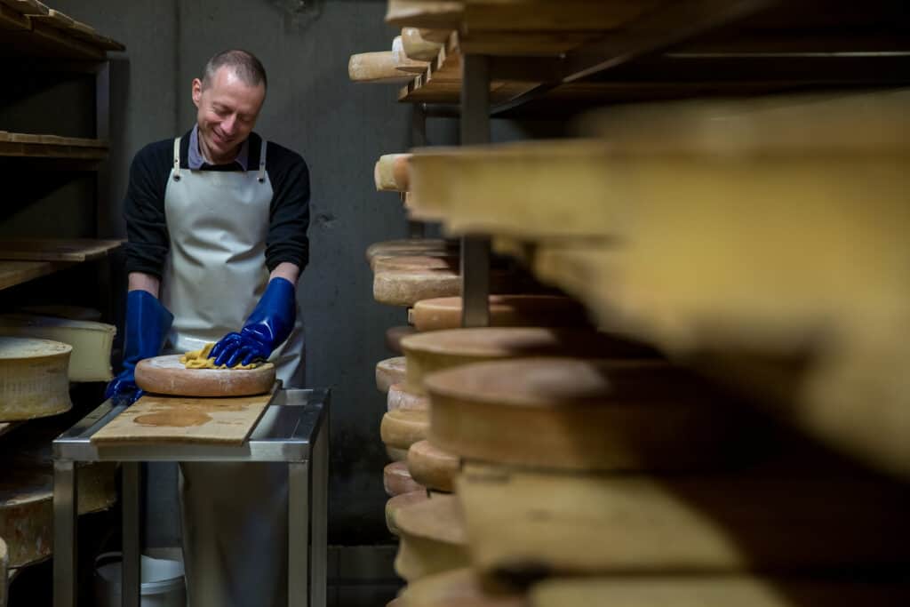 A cheesemonger making cheese in a cellar