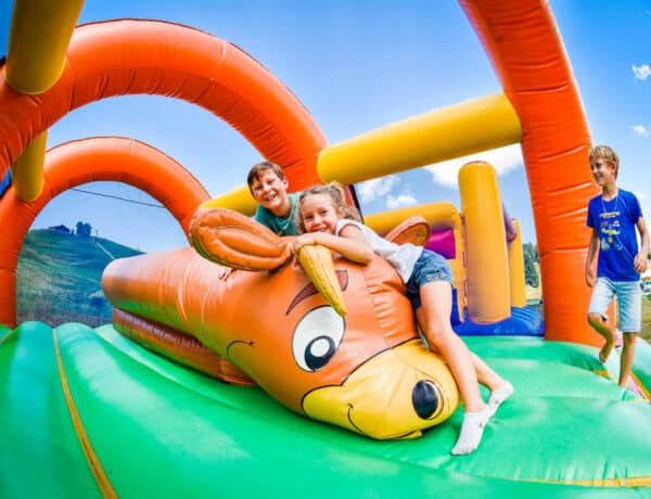 Une petite fille et deux garçons dans un château gonflable coloré.