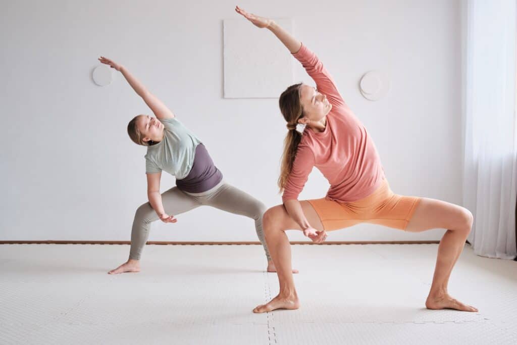 Two women practise yoga inside