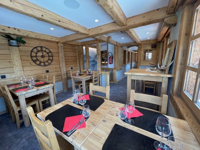 A restaurant dining room with wooden tables, wooden walls and tables laid for dinner