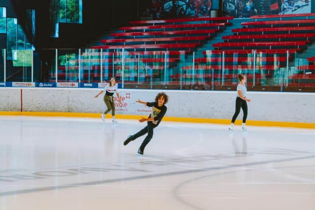 A young boy and two women skate on an indoor ice rink