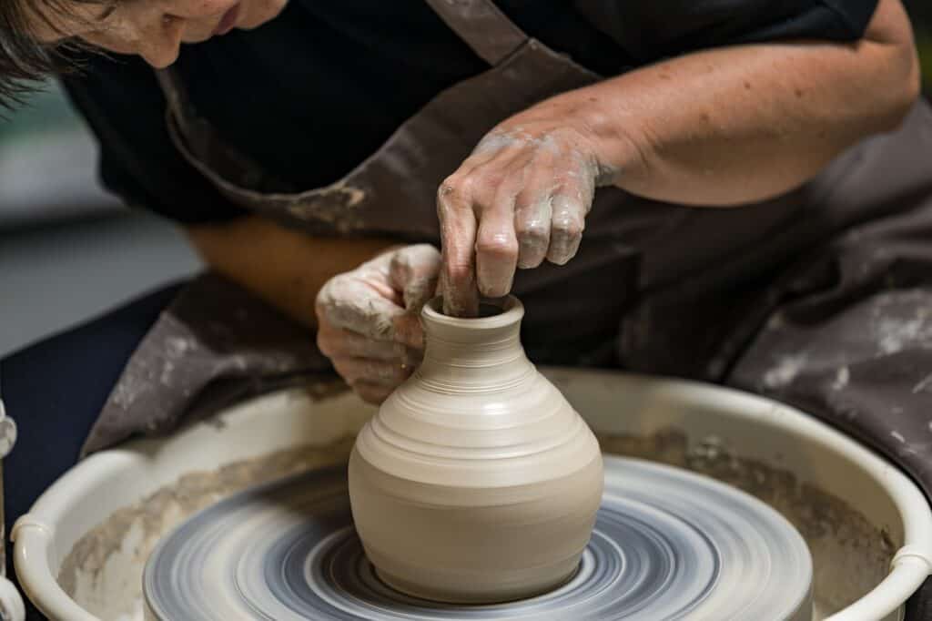 Une personne faisant de la poterie en tournant l'argile tout en le travaillant avec ses doigts.