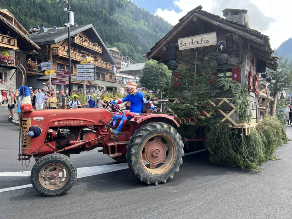 Un homme conduit un tracteur rouge dans une fête de village. 