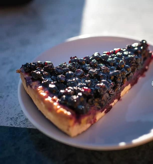 A slice of bilberry tart on a white plate