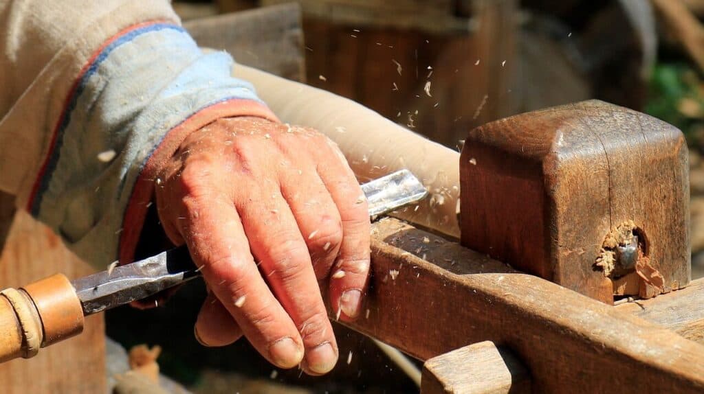 A man uses a chisel to work on some wood