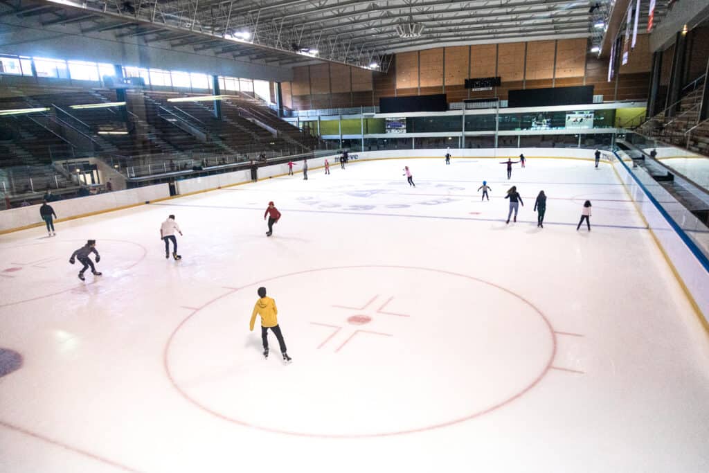 People skate on a large indoor ice rink