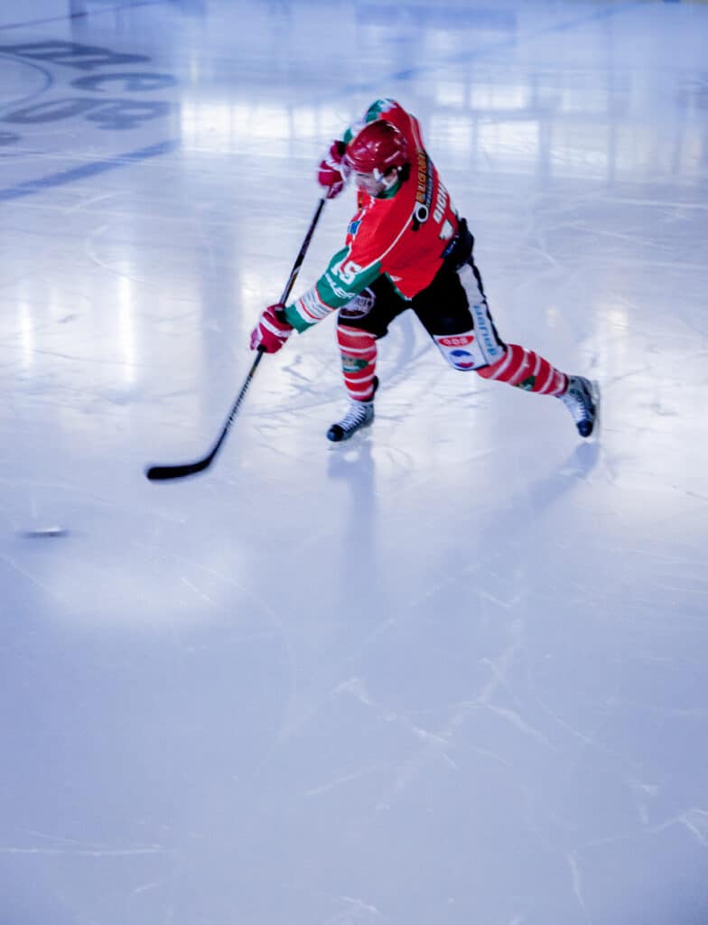 An ice hockey player hits a puck