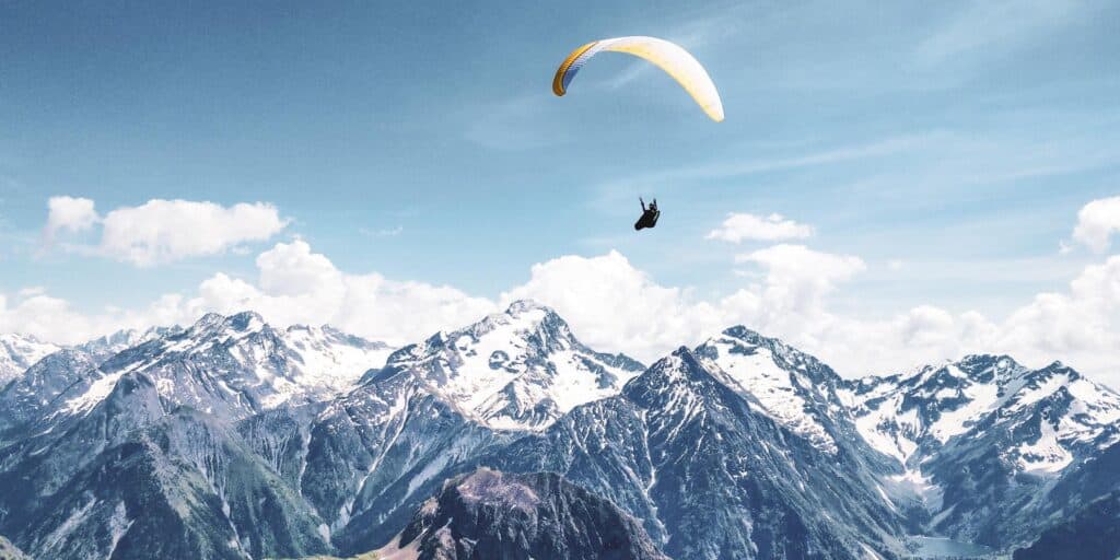 A paraglider soaring over the snowy peaks of the Alps