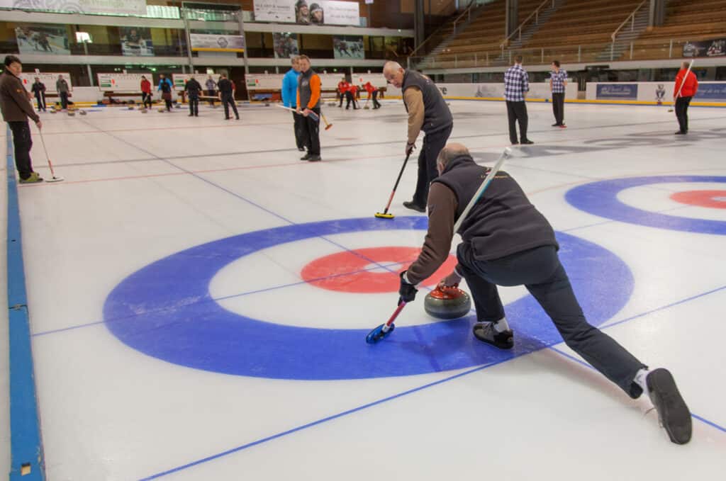 A group of men try curling on an ice rink