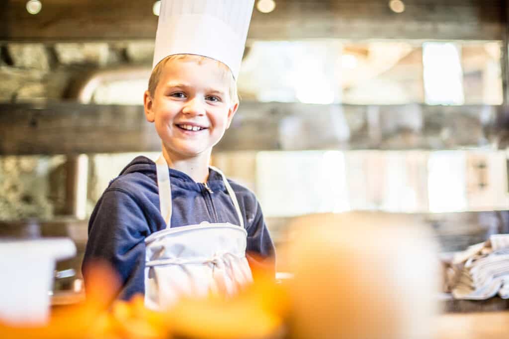 A young boy wearing a chefs hat and apron