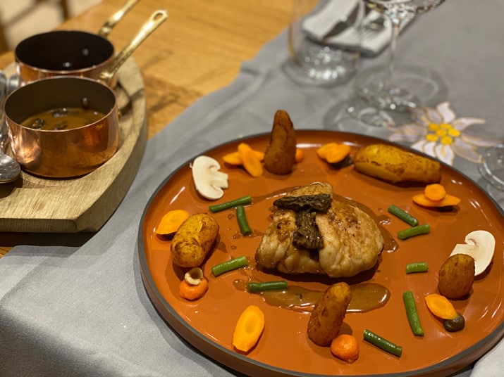 A dish of meat and vegetables on a terracotta plate