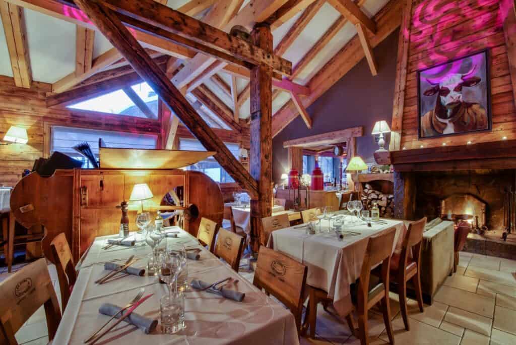 The cosy beamed dining room at La Scierie, with tables laid for dinner