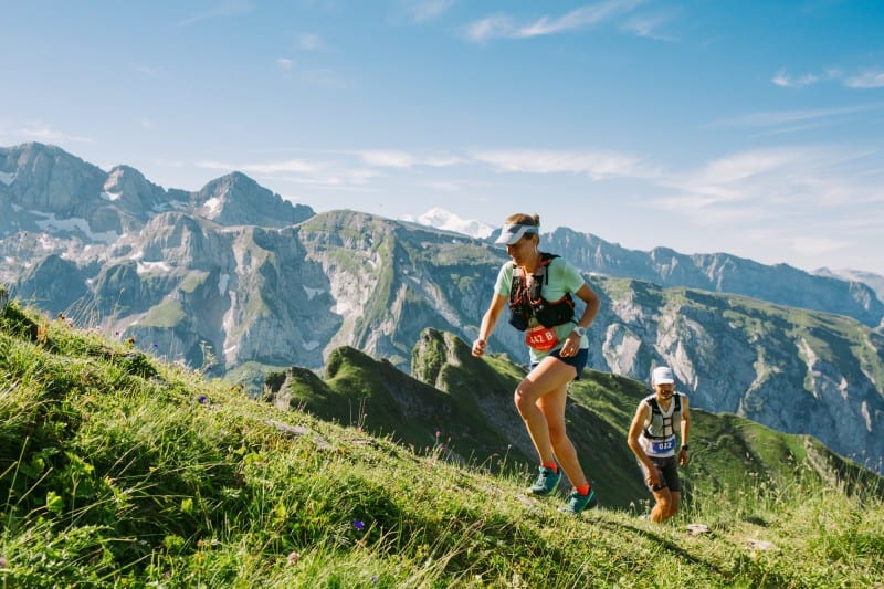 Two people hike a mountain path in summer
