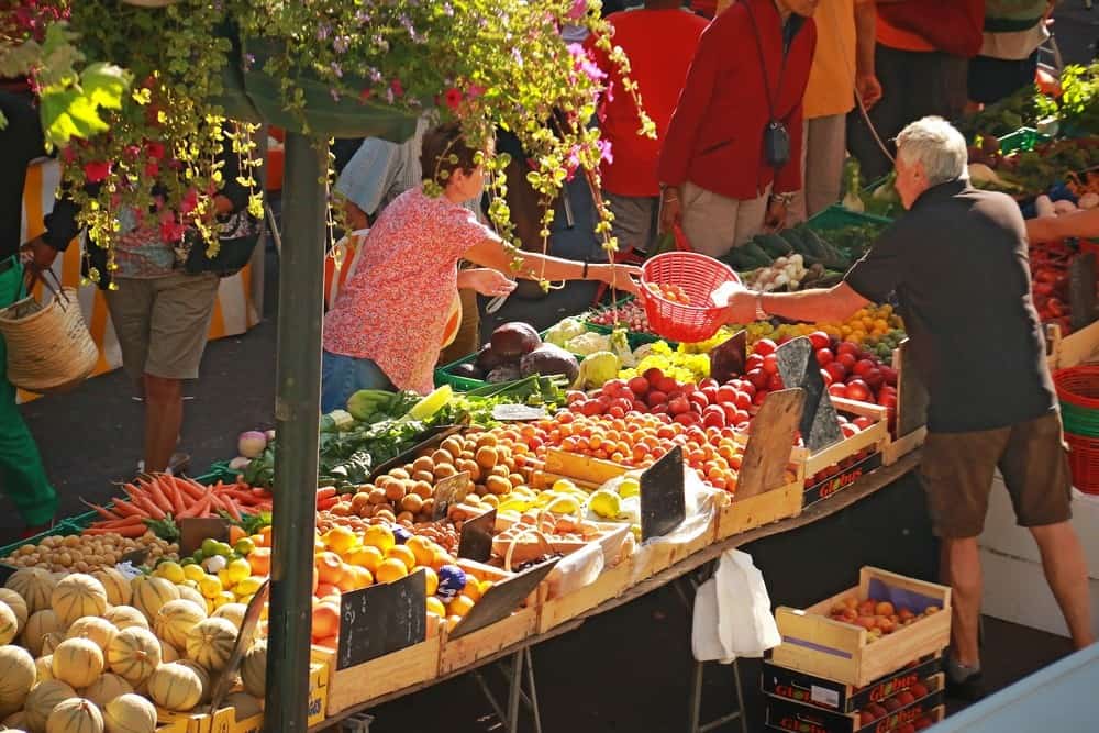 A woman buys fruit at a colourful market stall selling fruit and vegetables