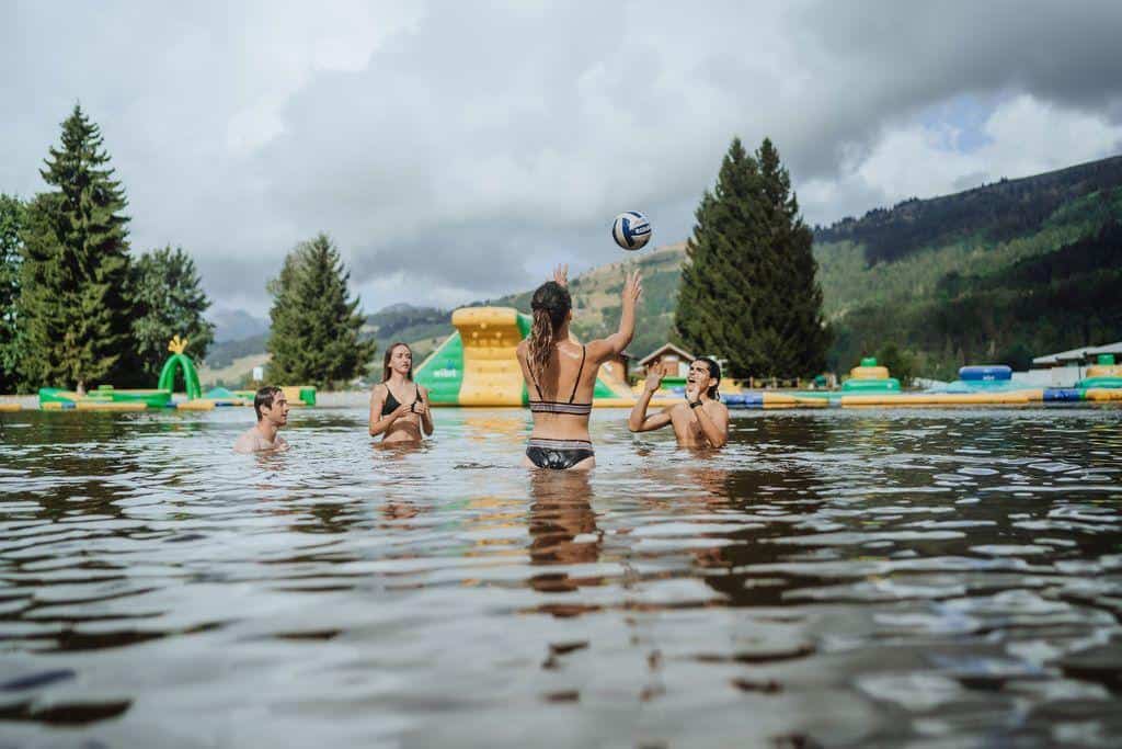 Des jeunes dans l'eau qui joue à se lancer un ballon.