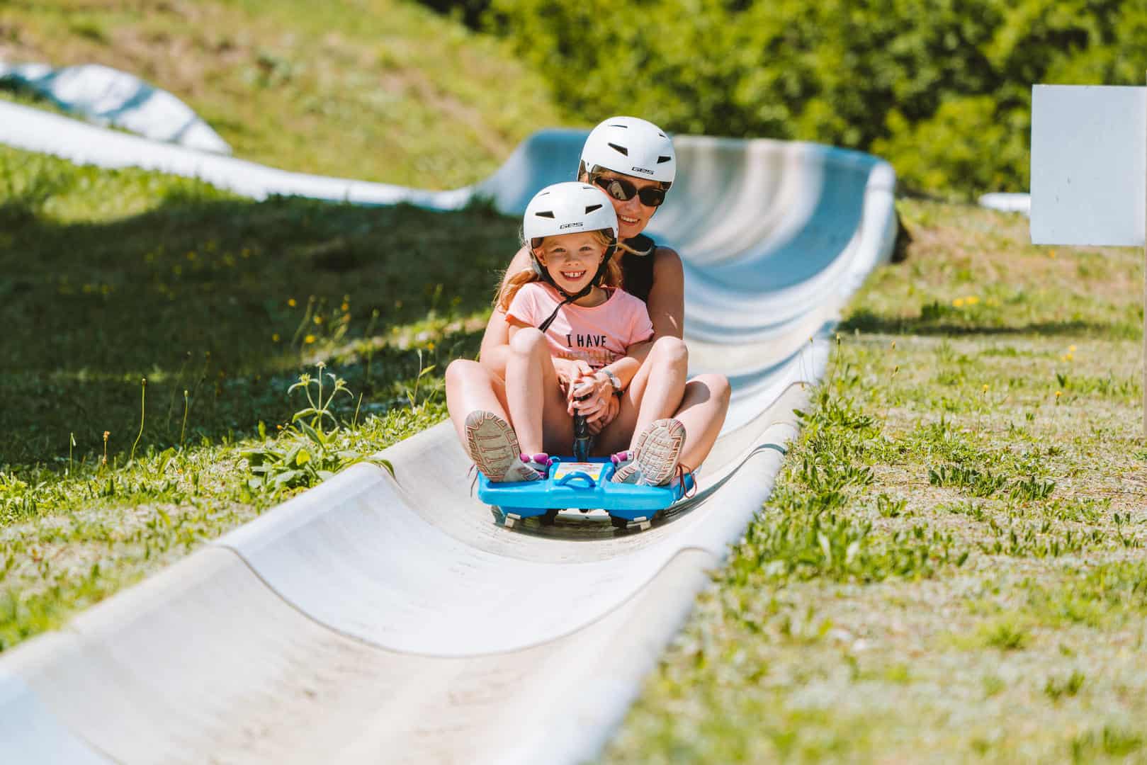 Une mère et sa fille dans une luge d'été, dévalant la pente.
