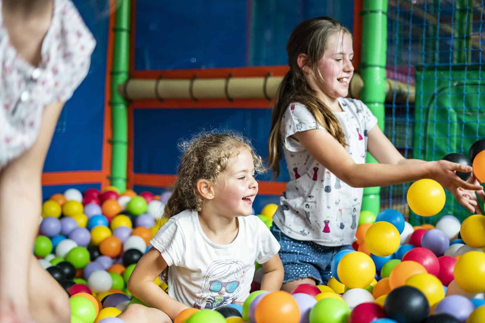 Young girls enjoying the ball pool, surrounded by plastic balls of various colours