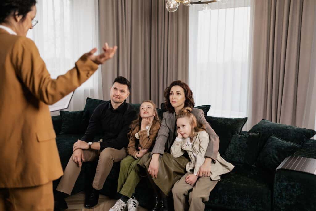 A family sit on a sofa whilst a woman speaks to them