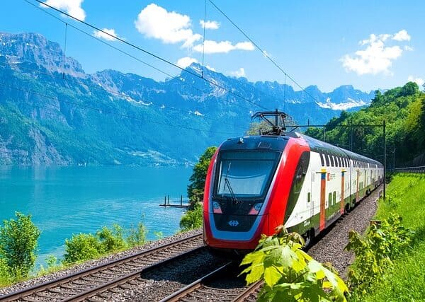 Un train à grande vitesse avec un lac et des montagnes en arrière-plan.