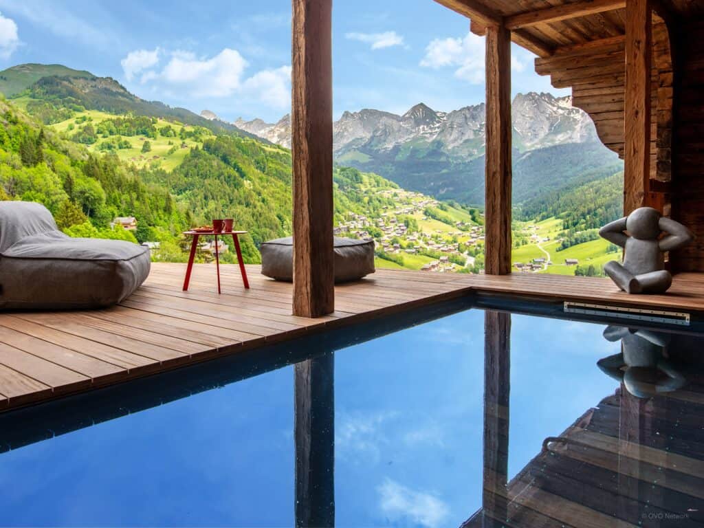 piscine extérieur avec une vue sur la montagne et des fauteuils autour de la piscine. 