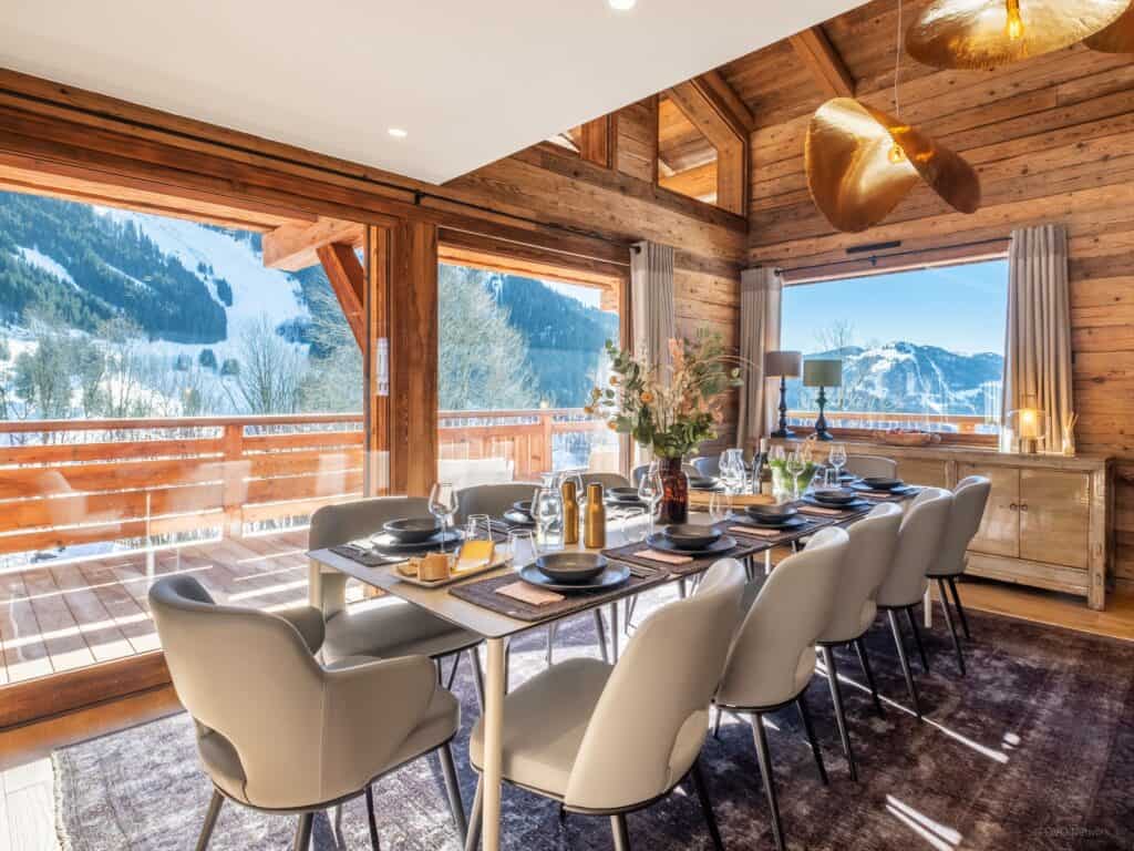 A dining table looking out onto mountains with a gold pendant lamp above it