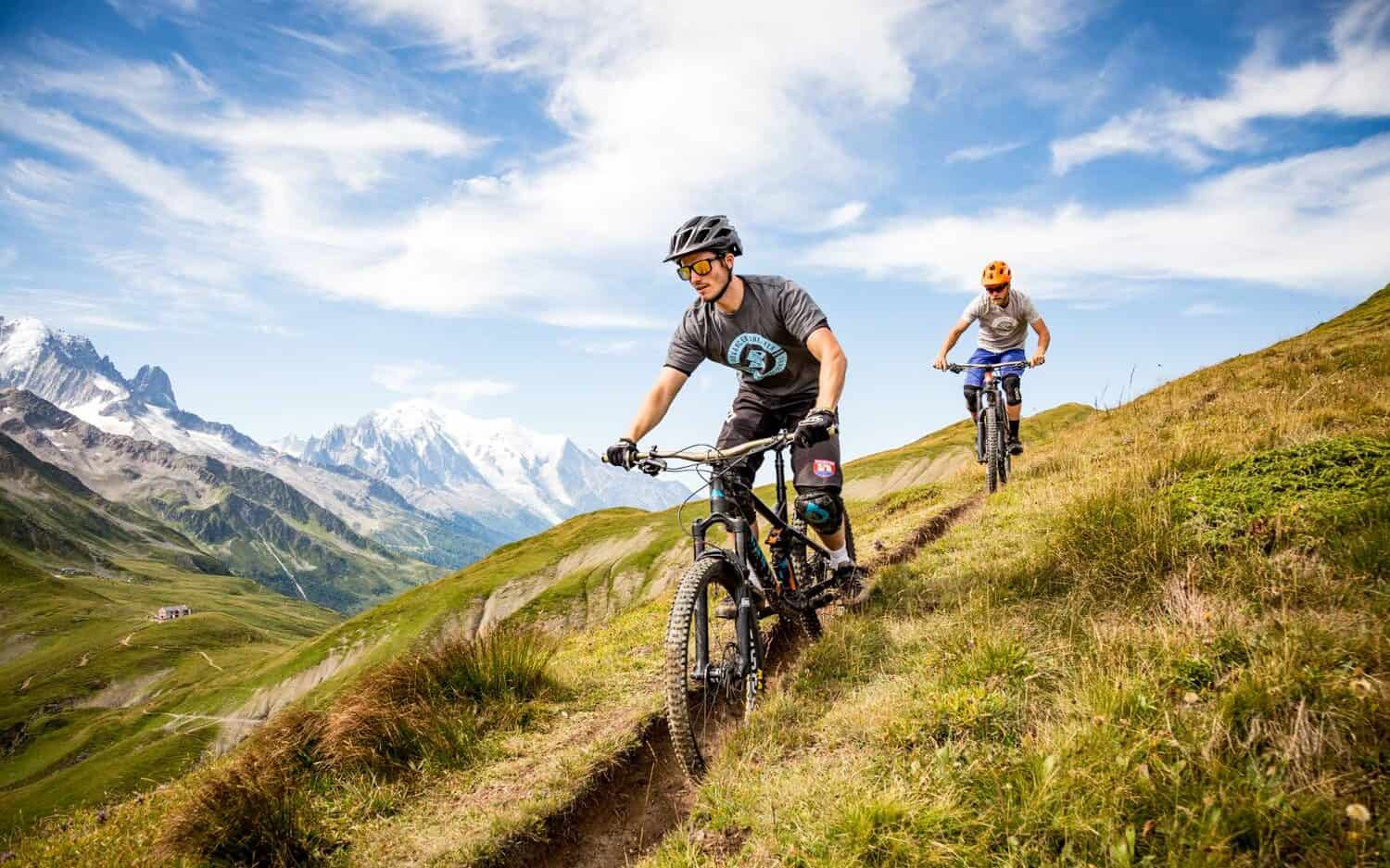 Two mountain bikers follow a grassy track in autumn