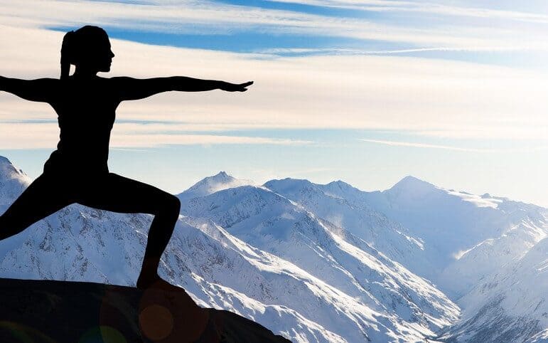 Jeune femme sportive pratiquant du yoga avec vue sur les Alpes enneigées.