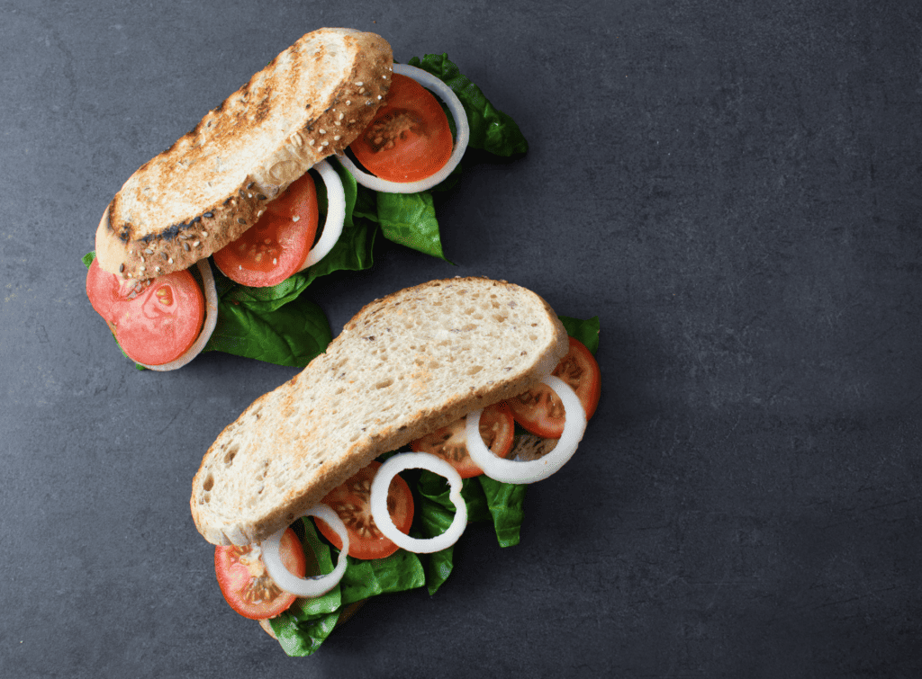 Two toasted sandwiches with salad, tomatoes and onion