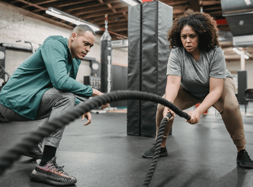 A woman does rope exercises with her coach