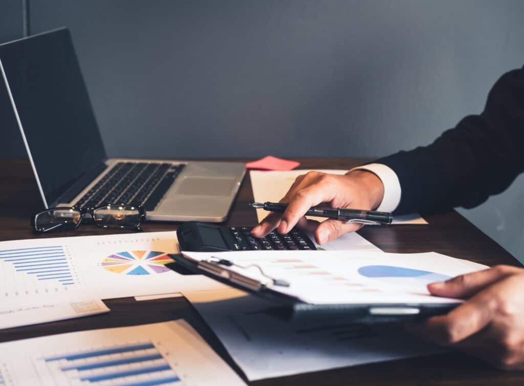 A man working at his desk with a laptop and clip files