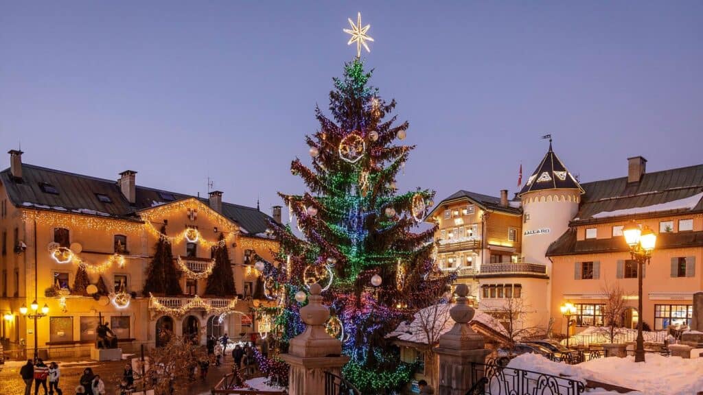 Sapin décoré et illuminé sur une place de village.