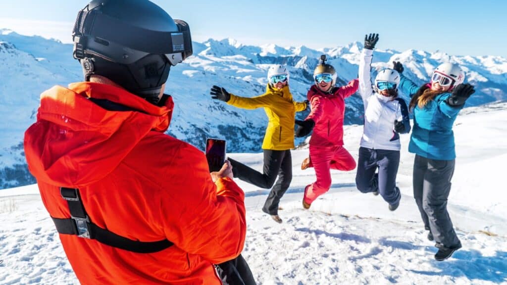 A skier takes a photograph of four other skiers on the slopes