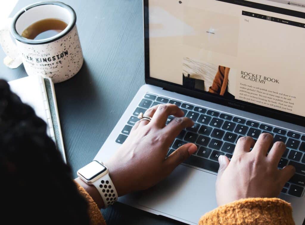 A person typing on the keyboard of their laptop
