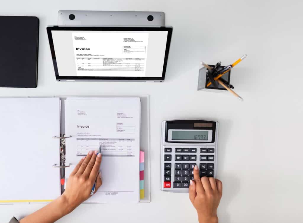 A bird's eye view of a person working at their desk with a laptop, folder and calculator