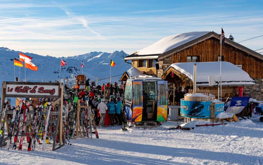 L'extérieur enneigé du Chalet du Sunny, avec rack à skis et montagnes.